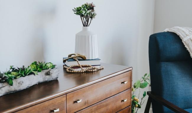 a dresser with a vase of plants on top