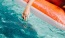 woman dangles her hand in the pool as she floats in an inflatable vessel