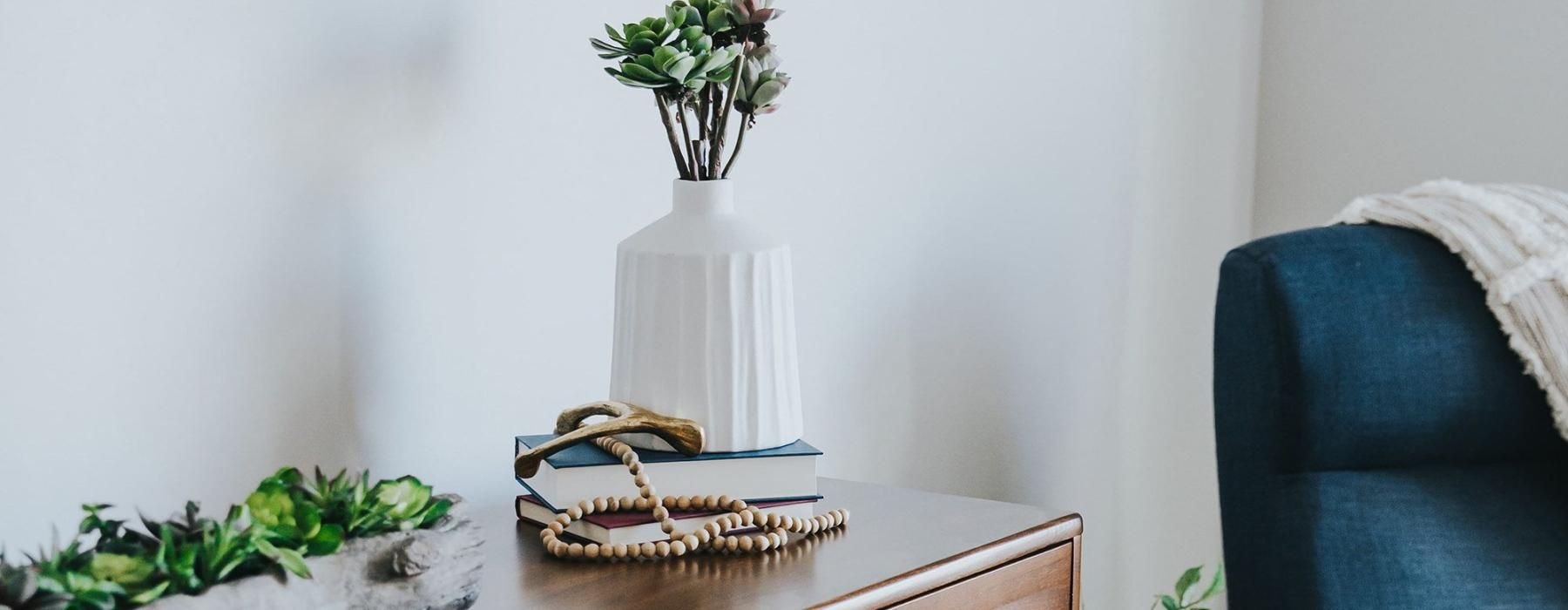 a dresser with a vase of plants on top